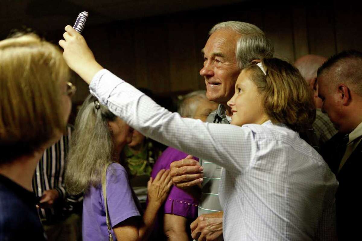 Gabby Harvey, 12, takes a photograph of herself with Congressman Ron Paul of Texas as he campaigns at the Northside Cafe in Winterset, IA on Saturday, August 27, 2011.