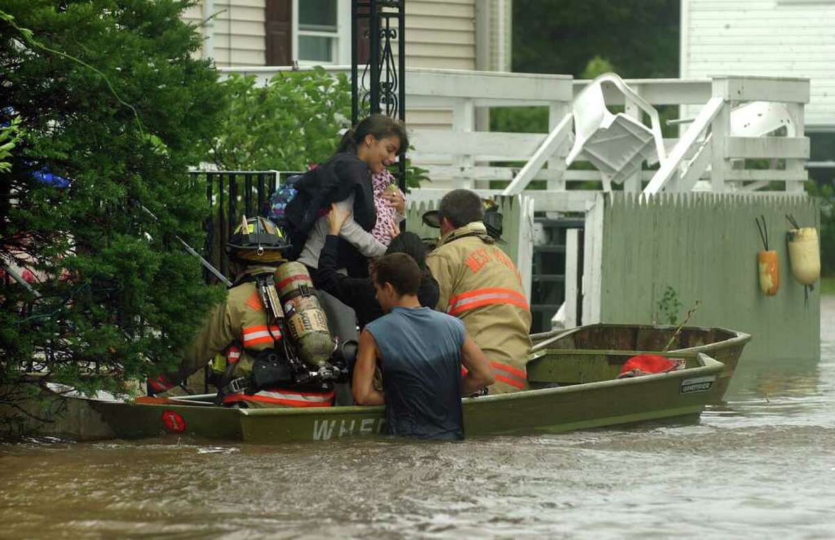 A local resident is rescued from her home by West Haven firefighters along Morse Street in West Haven, Conn. on Sunday August 28, 2011.
