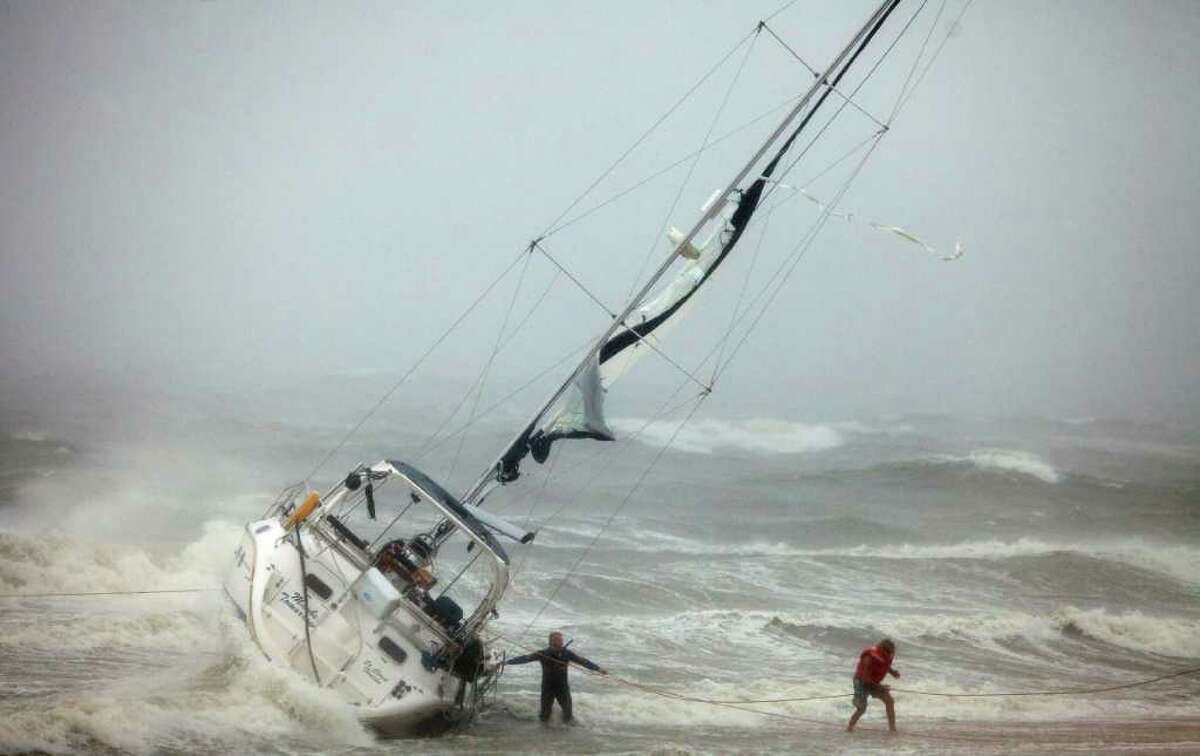 One of two people rescued from a sailboat, right, uses a line to make their way onto the beach on Willoughby Spit in Norfolk, Va., Saturday, Aug. 27, 2011, after they and another person were rescued from the boat that foundered in the waters of the Chesapeake Bay. A rescuer, left, waits for s second person to exit the boat. (AP Photo/TheVirginian-Pilot, Bill Tiernan) MAGS OUT