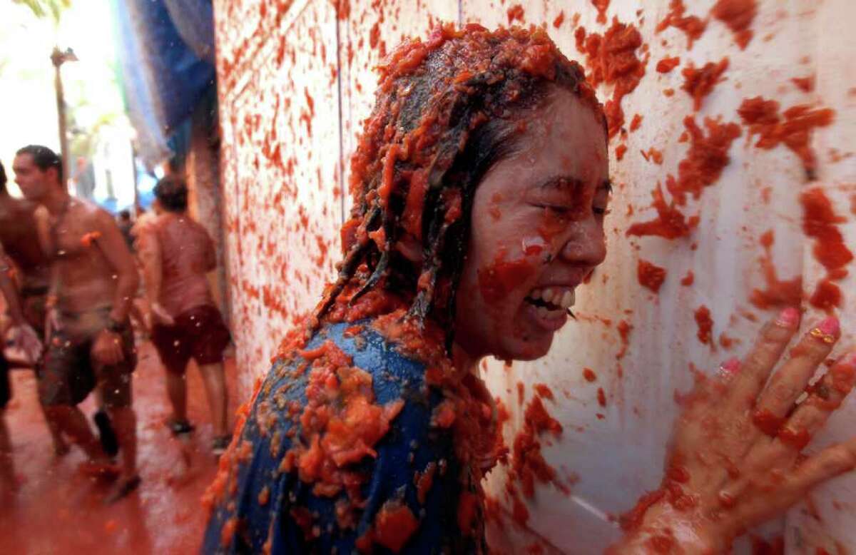 A reveler is pelted with tomatoes during the tomato fight fiesta in the village of Bunol, near Valencia, Spain, on Wednesday. Bunol's town hall estimated more than 40,000 people, some from as far away as Japan and Australia, took up arms Wednesday and pelted each other with 120 tons of ripe tomatoes in the yearly food fight known as the 'Tomatina' now in its 66th year. (AP Photo/Alberto Saiz)