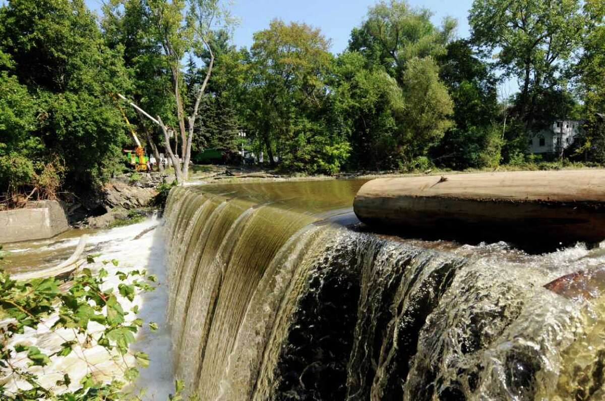 Water flows over the Poesten Kill Dam as crews work on the process of clearing a tree in Troy, NY, on Friday Sept.2, 2011.( Michael P. Farrell/Times Union)