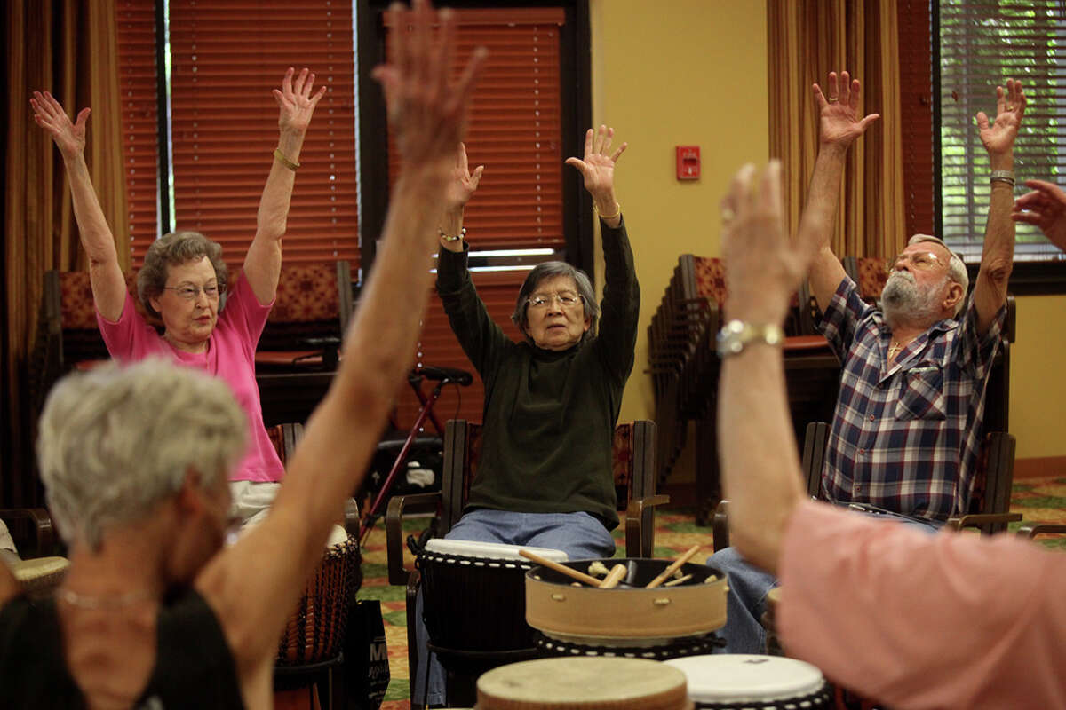 Residents, including Norma Whitt (from left), Fing Young and Richard Saldivar, stretch after participating in a drum circle at Morningside Ministries at The Meadows in July. Drum circle facilitator Kevin Cooley says community drumming creates an informal support group. LISA KRANTZ / EXPRESS-NEWS