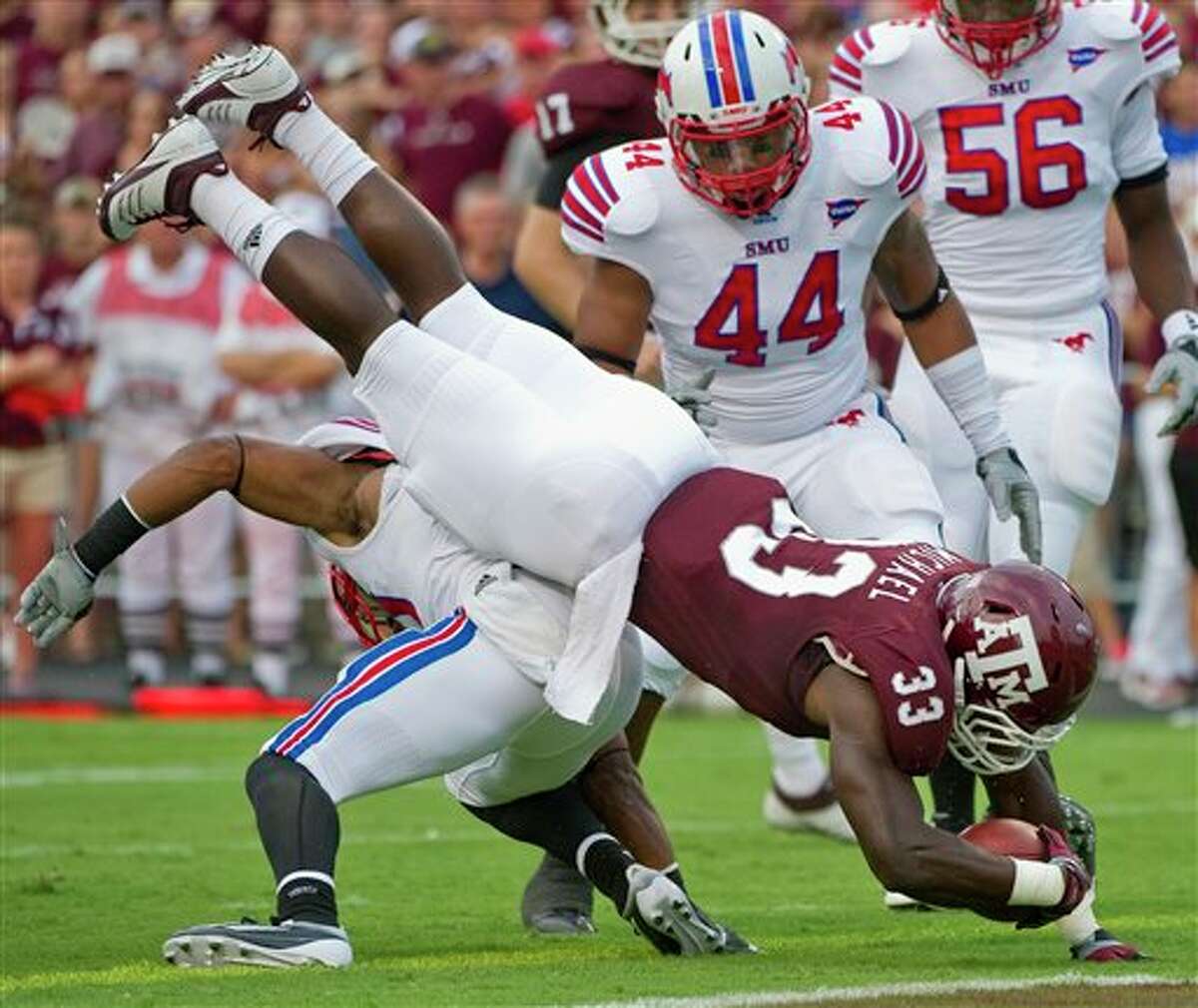 Texas A&M running back Christine Michael (33) dives over SMU's Ryan Smith, bottom, as Taylor Reed (44) helps during the first quarter of an NCAA college football game, Sunday, Sept. 4, 2011, in College Station, Texas. (AP Photo/Dave Einsel)