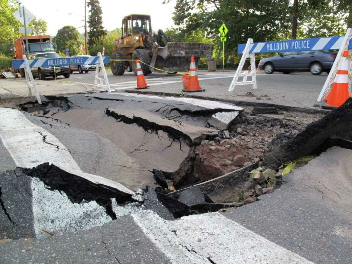 In this Sept. 2, 2011 photo, a front loader passes a sink hole in a Millburn, N.J. intersection. Officials say it could take months just to make basic repairs due to damage caused by Hurricane Irene. Many permanent fixes will have to wait until the spring. (AP Photo/Chris Hawley)