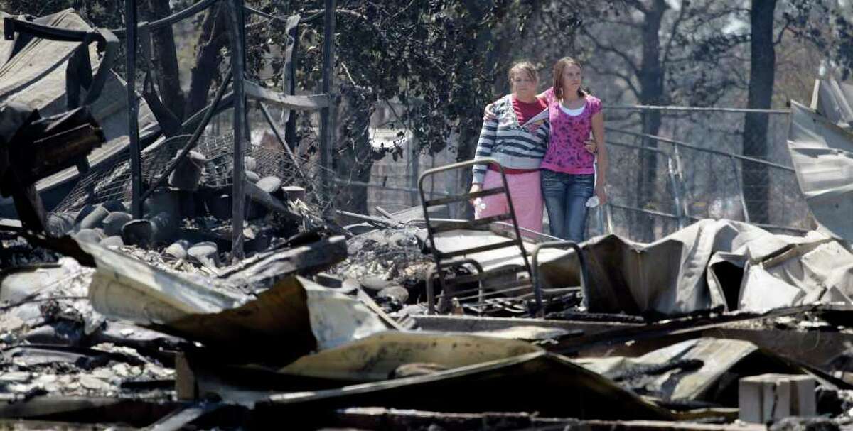 Sisters Laura, left, and Michelle Clements survey their fire-destroyed home, Tuesday, Sept. 6, 2011, in Bastrop, Texas. The Clements lost their home to fires Monday. (AP Photo/Eric Gay)