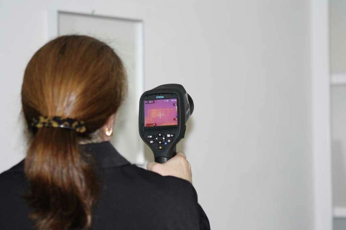 Sheila Courtney, senior risk manager for PURE Insurance, uses an infrared camera to search a new policyholder s home for cold spots that could indicate leaking. Homeowners who install a leak detection system can get a discount on their insurance rate.