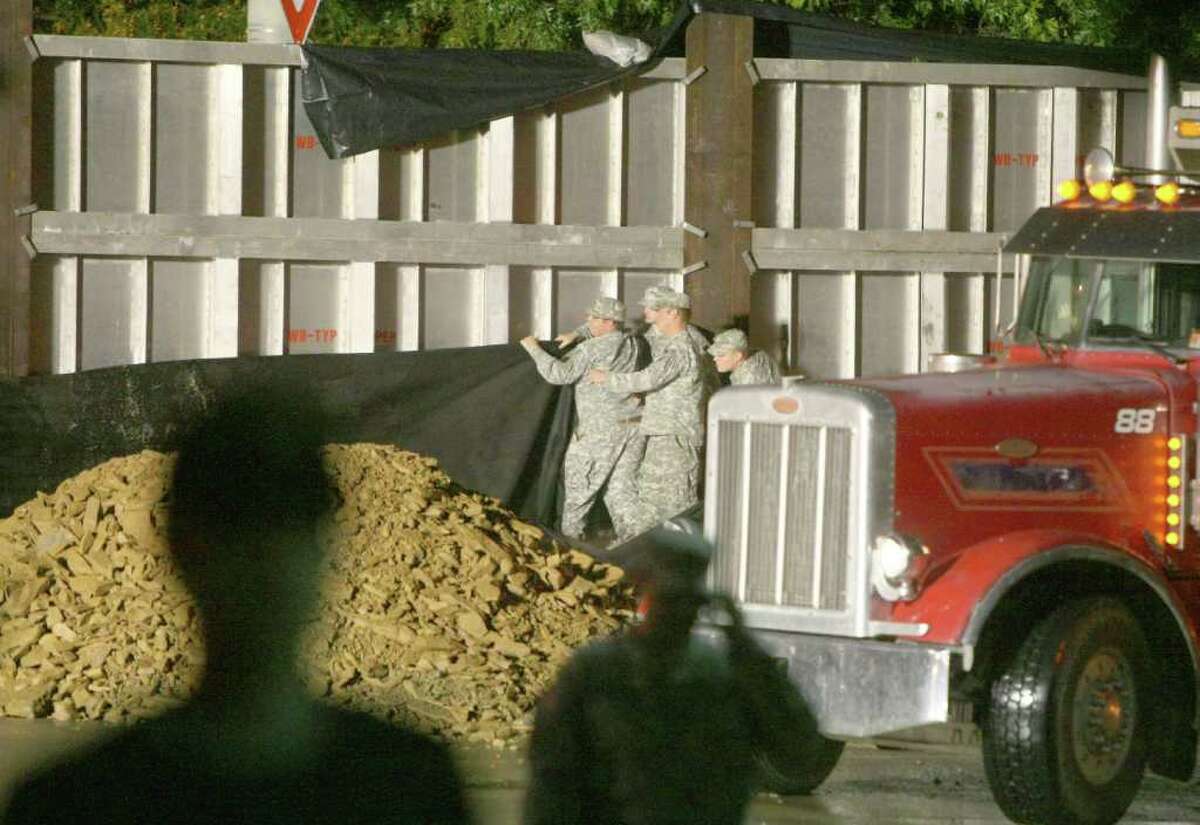 National Guardsmen place mesh tarping and loads of dirt and other materials on the Market Street Bridge flood gate in an effort to stop water that is pouring from the gate's cracks in Wilkes-Barre, Pa., on Thursday Sept. 8, 2011. Nearly 100,000 people from New York to Maryland were ordered to flee the rising Susquehanna River on Thursday as the remnants of Tropical Storm Lee dumped more rain across the Northeast, closing major highways and socking areas still recovering from Hurricane Irene.