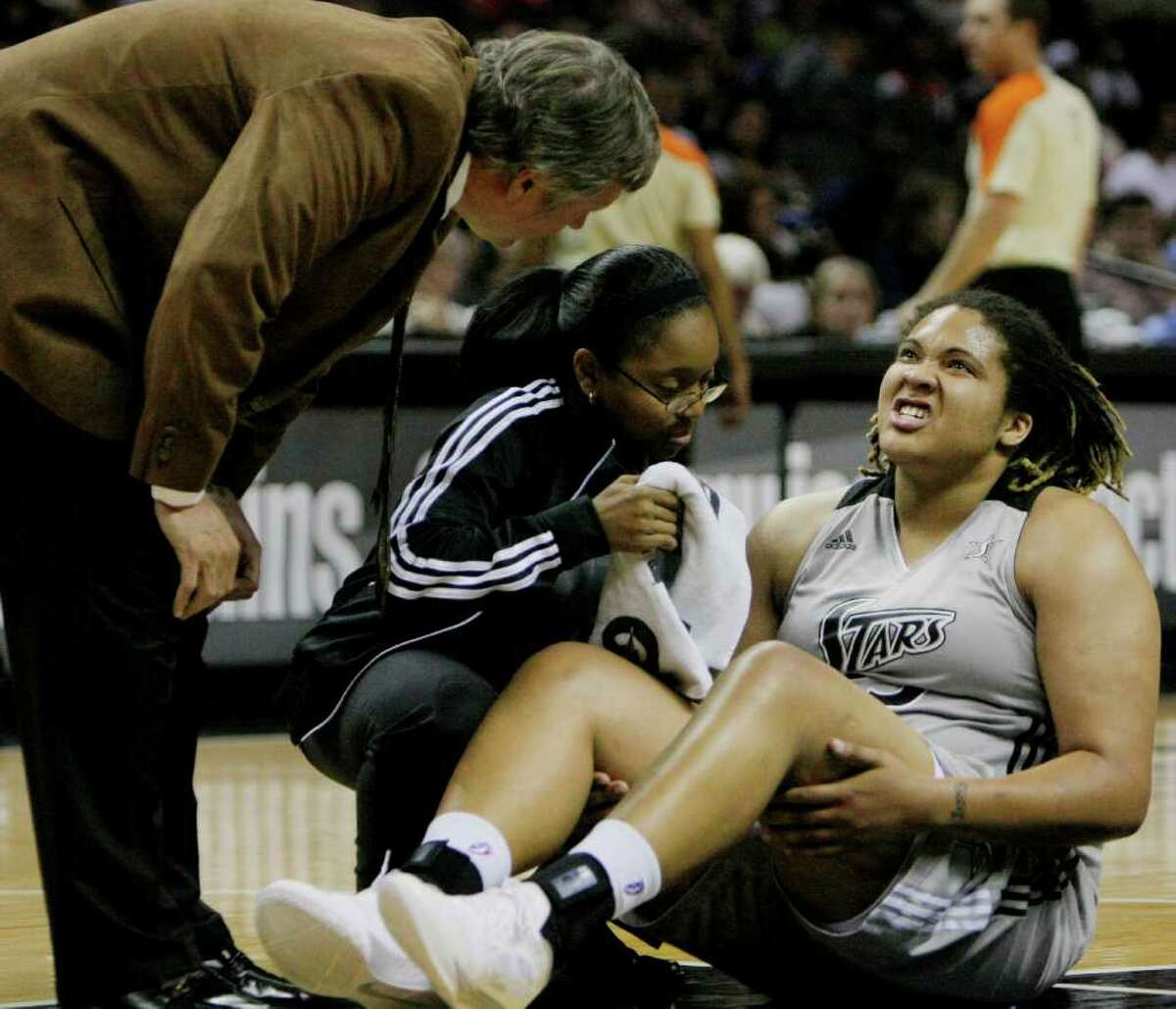 Silver Stars head coach Dan Hughes, left, looks on as Stars' Danielle Adams, right, is checked out after suffering an injury during the first half of a WNBA basketball game against the Washington Mystics, Saturday, Sept. 10, 2011, in San Antonio.