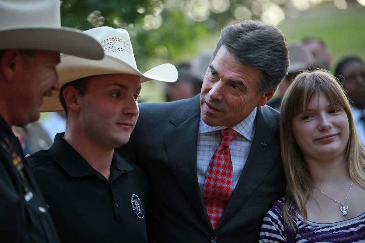 Gov. Rick Perry talks with Bob Goerlitz, president of the Harris County Deputies' Organization, and his children, Michelle Goerlitz, 13, and James Goerlitz, 20, after Perry led a Memorial Service at the 9/11 Monument, which features two steel columns from ground zero, at the Texas State Cemetery in Austin on Sunday, Sept. 11, 2011.