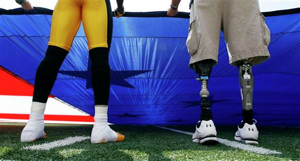 Pittsburgh Steelers defensive back William Gay, left, holds an American flag next to Mike Martinez, who lost his legs while serving with the U.S. Marines in Afghanistan, before an NFL football game against the Baltimore Ravens, Sunday, Sept. 11, 2011, in Baltimore. Today marks the 10th anniversary of the 9/11 attacks. (AP Photo/Patrick Semansky)