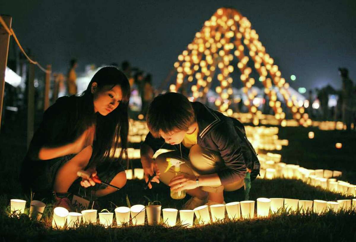 Local residents light a candle at a park during a memorial event marking six months after the March 11 earthquake and tsunami in Iwanuma city, Miyagi prefecture, Sunday, Sept. 11, 2011. As the world commemorates the 10th anniversary of the World Trade Center attacks, Sunday is doubly significant for Japan. It marks exactly six months since the disasters. (AP Photo/Kyodo News) JAPAN OUT, MANDATORY CREDIT, NO LICENSING IN CHINA, FRANCE, HONG KONG, JAPAN AND SOUTH KOREA