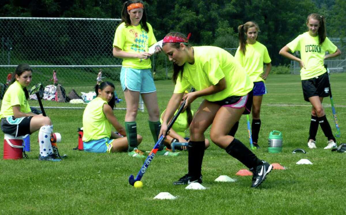 SPECTRUM/Marisa McLaughlin takes her turn dribbling her way through a course as teammates, from left to right, Deanna Barone, Vienna Pallisco, Olivia Monteiro, Katelyn Robinson and Elizabeth Peterson check out her technique during practice for the 2011 New Milford High School field hockey season. September 2011