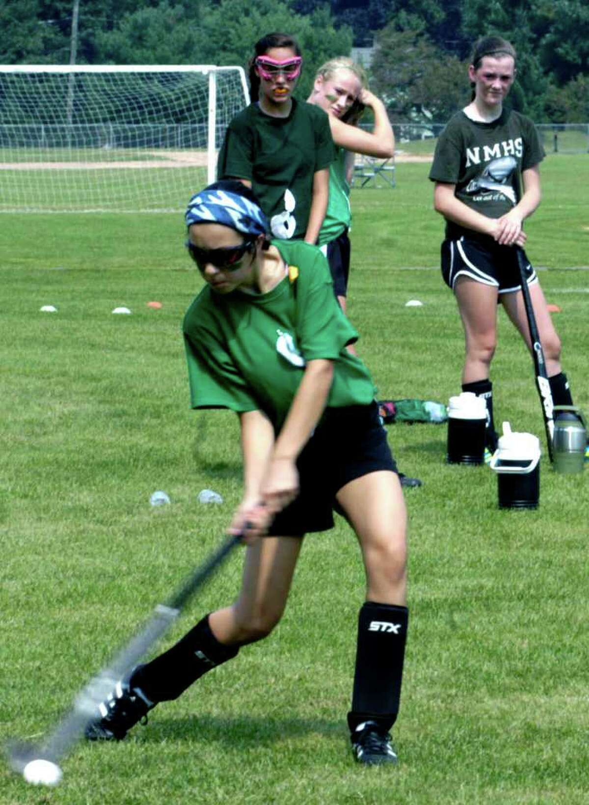 SPECTRUM/Rebecca Andrade drives the ball toward the goal as teammates Alex Carey,back left, Taylor Duffany and Brianna Benz, right, await their trun during practice for the 2011 New Milford High School field hockey season. September 2011