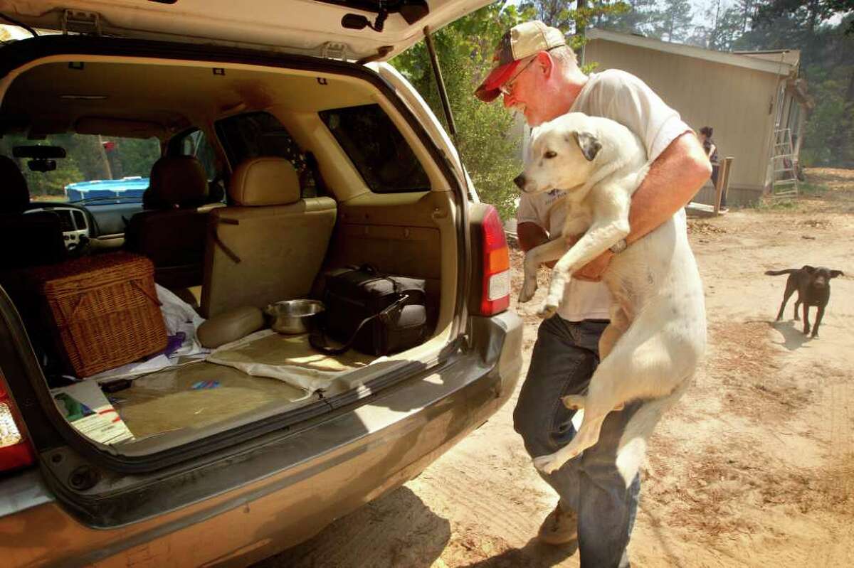 Nathan Trammell loads the first of the family's two dogs, Tuesday, into his van after the fire department declared a mandatory evacuation because of wildfires in Cass County, Tuesday, Sept. 6, 2011, in Linden, Texas. One of the most devastating wildfire outbreaks in Texas history left more than 1,000 homes in ruins Tuesday and stretched the state's firefighting ranks to the limit, confronting Gov. Rick Perry with a major disaster at home just as the GOP presidential contest heats up. (AP Photo/ The Texarkana Gazette,Evan Lewis)