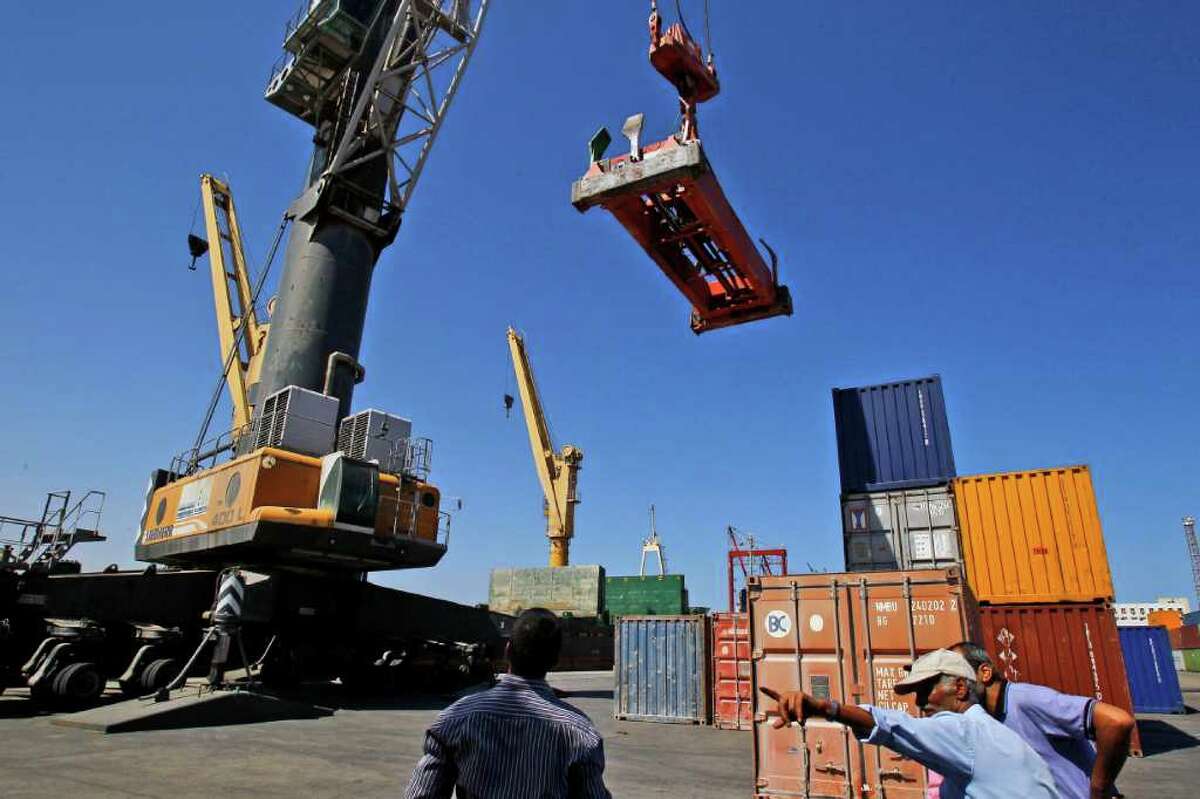 In this photo taken Monday, Sept. 12, 2011, Tripoli port employees gestures next to containers in Tripoli, as Libya reopens its doors to business after seven months of fighting, even as former rebels still hunt for ousted dictator Moammar Gadhafi. Airlines are readying their return to Libya, ports largely shuttered during the fighting are receiving cargos and foreign oil companies that had fled the country's civil war are making tentative steps back. (AP Photo/Francois Mori)