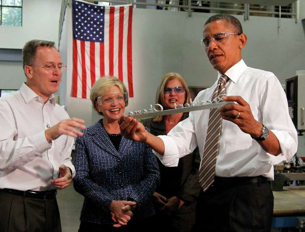 CHUCK LIDDY: RALEIGH NEWS & OBSERVER BUSINESS VISIT: President Barack Obama examines a deskplate carved from aluminum presented to him during his visit to WestStar Precision, a manufacturing plant in Apex, N.C., on Wednesday as WestStar owner Ervin Portman, Susan Portman and Gov. Bev Perdue look on.