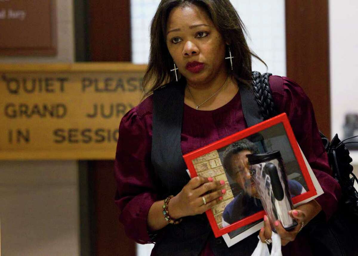 Evangeline Campbell leaves the Harris County grand jury room Wednesday carrying a photo of her late father, inmate Norman Ford Hicks.