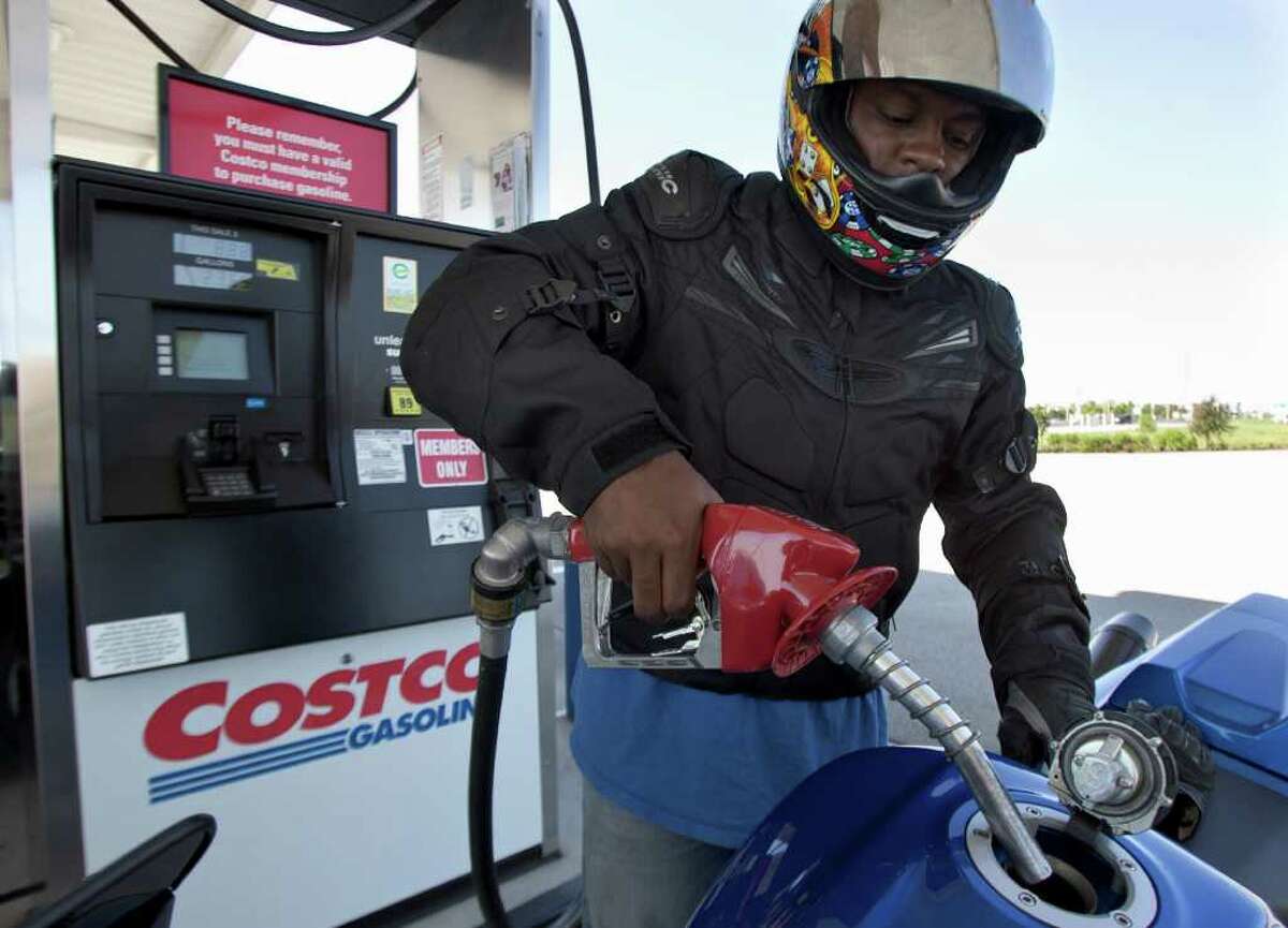 In this Aug. 9, 2011 photo, Reggie Thomas fuels his motorcycle at a COSTCO gas station in Omaha, Neb. Sharp price increases for gas and food have pushed up most measures of inflation this year. That has reduced consumers' purchasing power, cut into their ability to spend on other items and weakened the economy. (AP Photo/Nati Harnik)