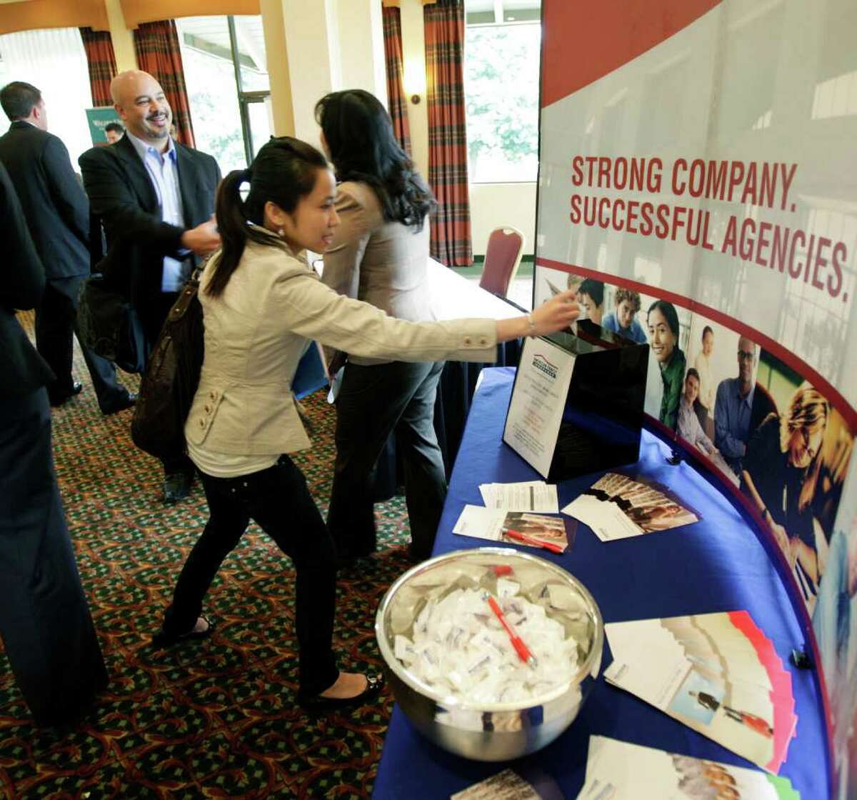 Job-seeker Michael Kautzman, left, talks to Tara Tran, right, a district manager for American Family Insurance, about employment possibilities as Linh Phung, center, puts a completed form in a collection box, during a National Career Fairs job fair, Wednesday, Sept. 14, 2011, in Bellevue, Wash. The number of people applying for unemployment benefits last week jumped to the highest level in three months, a sign that layoffs could be increasing. (AP Photo/Ted S. Warren)