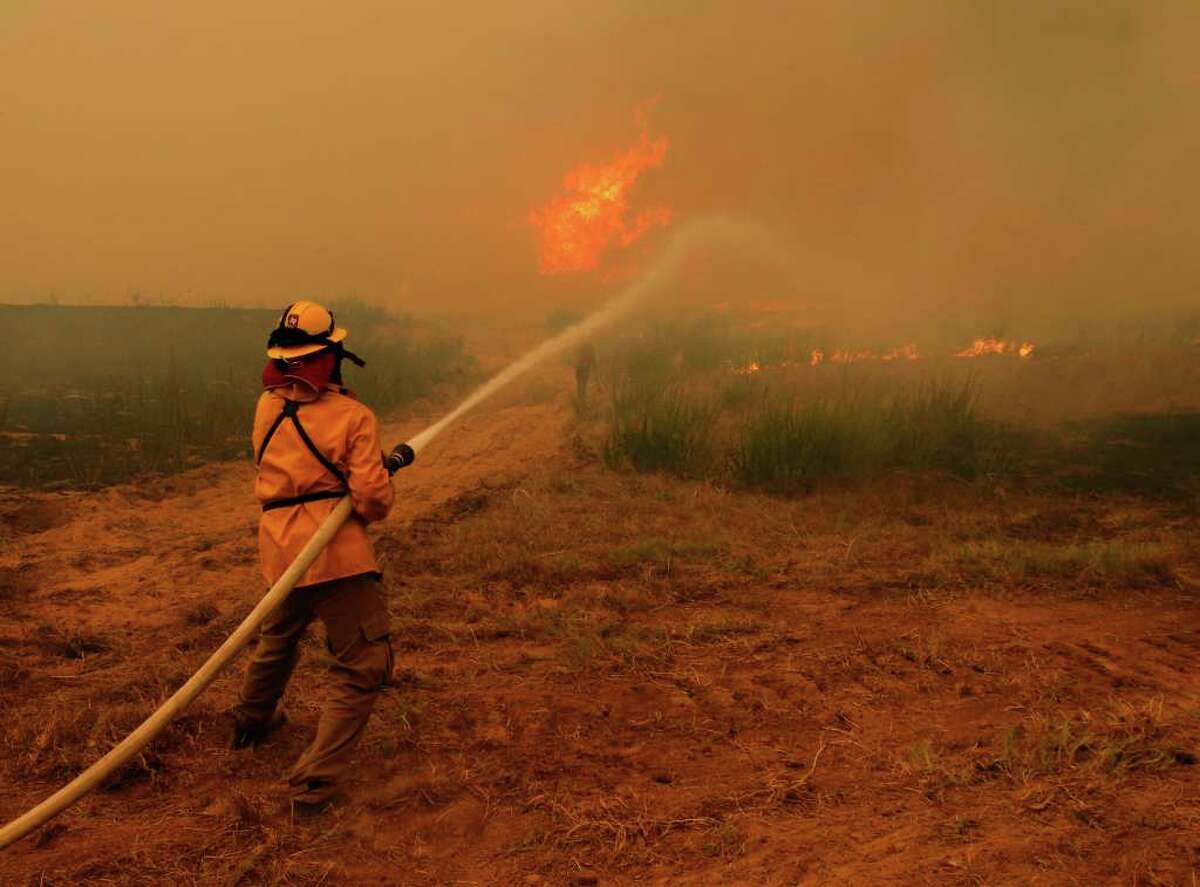 Heart of the Pines volunteer firefighter Gary Hicks fights a wildfire Monday near Bastrop. Many volunteers like Hicks have been battling the wildfires raging across the state without proper gear.