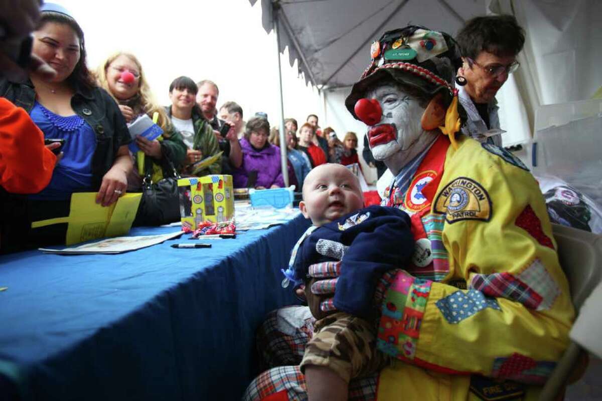 J.P. Patches holds onto Deano Dixon, 7 months, as crowds come to see the legendary clown during his final public performance on Saturday, Sept. 17, 2011 at the Fall Fishermen's Festival in Ballard. The man behind the legendary clown, Chris Wedes, is hanging up the costume after decades of entertaining kids in the Pacific Northwest.