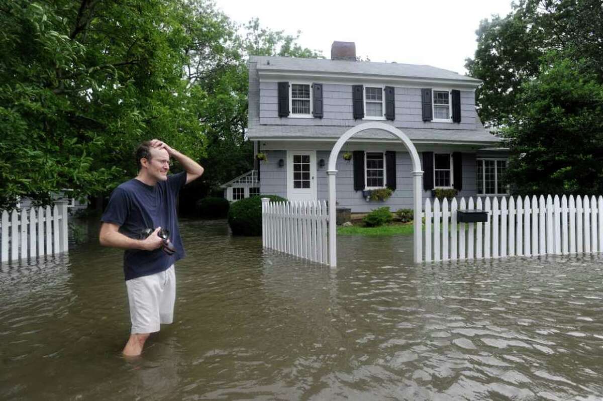 A man who would give his name as only Charlie puts his hand to his head in front of his flooded Meadowbank Road home in Old Greenwich during Hurricane Irene Sunday morning, Aug. 28, 2011.