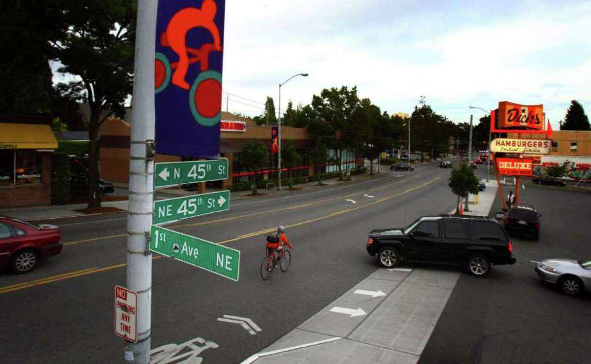 A bicycle rider has to swerve as a car pulls out into traffic on NE 45th Street in Seattle's Wallingford neighborhood. The stretch of road in front of Dicks Drive-In is the most dangerous in the city for bicyclists, with over 6 collisions there over three years.