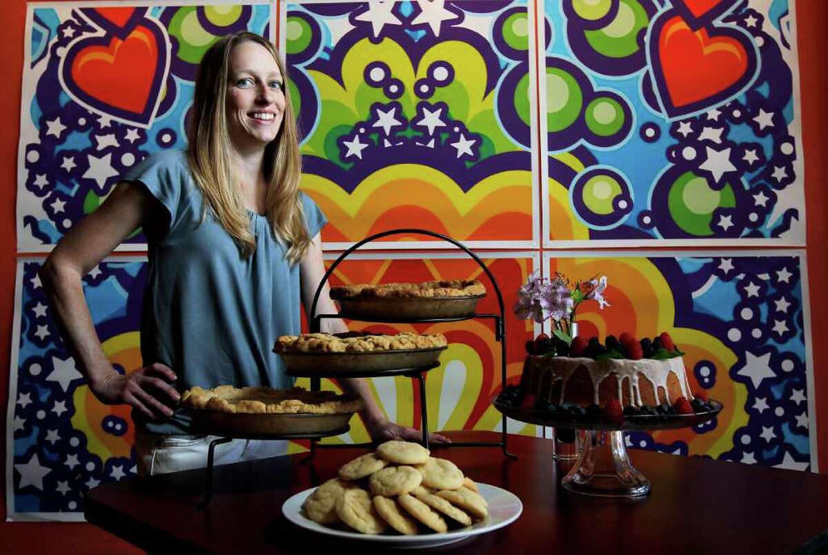 Leanna Fossler poses with an assortment of her pastries including a cream cheese pound cake, pecan pie a Texas Peach and Blueberry pie, and a Buttermilk pie at Heights Ashbury Coffeehouse, a bakery-coffeehouse where her pastries soon will be sold, Friday, Aug. 5, 2011,in Houston. Behind Fossler is artwork by Charlie Hardwick. ( Karen Warren / Houston Chronicle )