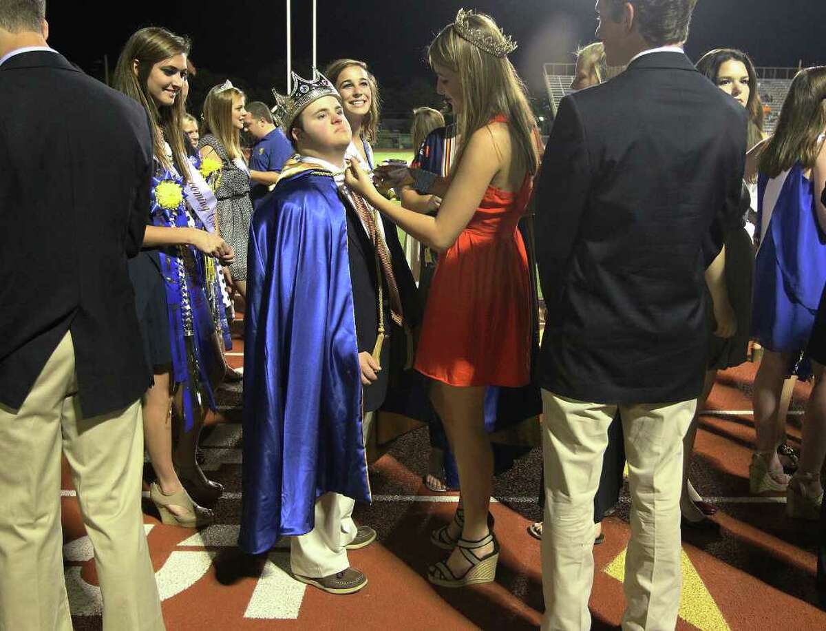 Alamo Heights homecoming king Drew Boynton (center) gets help from Abby Cavender in putting on a cape shortly before homecoming ceremonies at Alamo Heights High School on Friday, Sept. 23, 2011. Boynton who has Down syndrome was selected by the entire school to be the king at homecoming.
