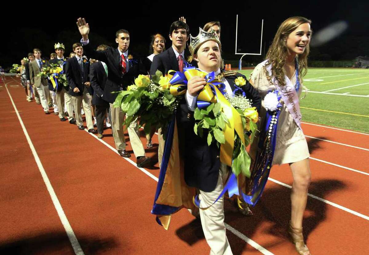 Alamo Heights homecoming king Drew Boynton (center) joined by homecoming court duchess Lena Carr (right) leads the rest of the court to start the school's homecoming ceremonies during halftime of their football game against Lockhart High at Alamo Heights High School on Friday, Sept. 23, 2011. Boynton who has Down syndrome was selected by the entire school to be the king at homecoming.