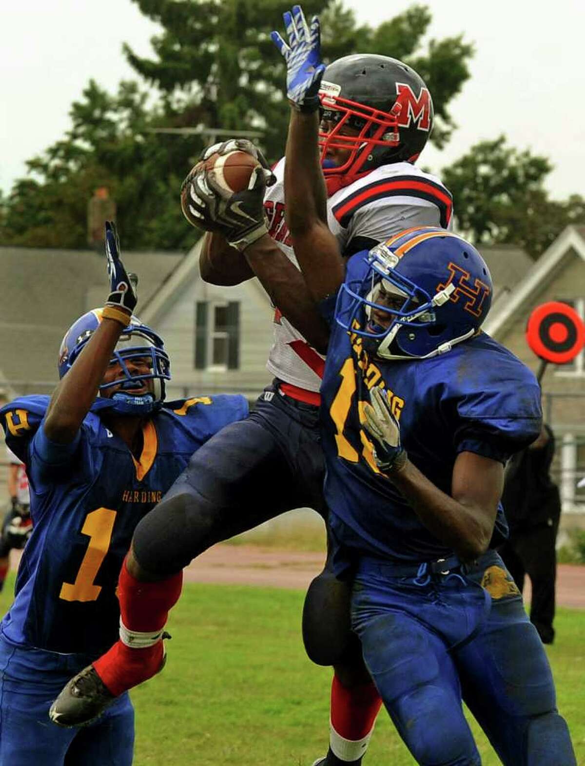 McMahon's #34 Chris Jerome catches the ball in the endzone for a touchdown during boys football action against Harding in Bridgeport, Conn. on Saturday September 24, 2011. Harding players are Jahaad Williams, left, and Antwaine Clark, right.