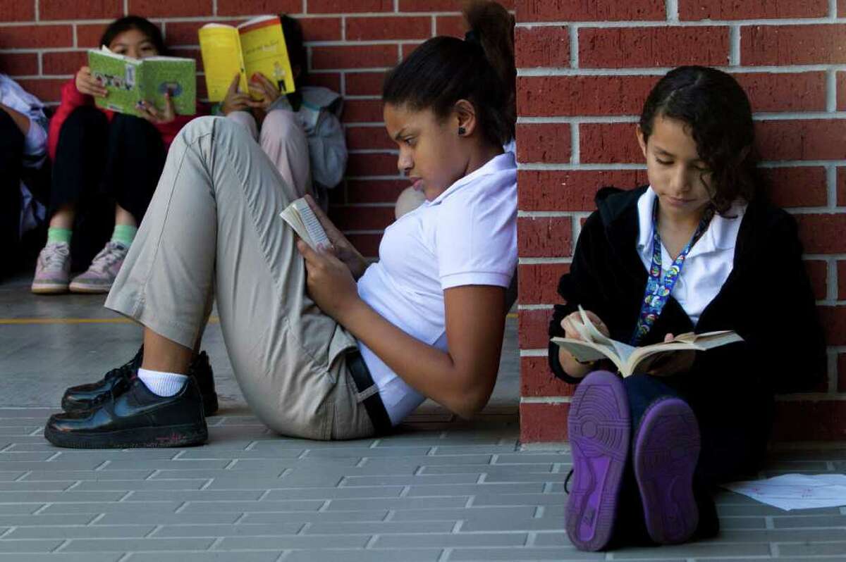 Sixth-graders Kayla Houston, center, and Joceline Gonzalez read outside in the courtyard at Caraway Intermediate School. Students at the school are so hooked on reading they've even created weekly book clubs.