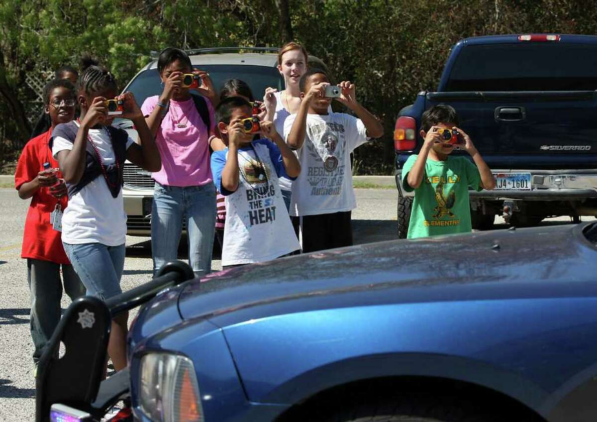 Children from SAMMinistries photograph a police car in Castle Hills as part of the “Pictures of Hope” program for youngsters in shelters.
