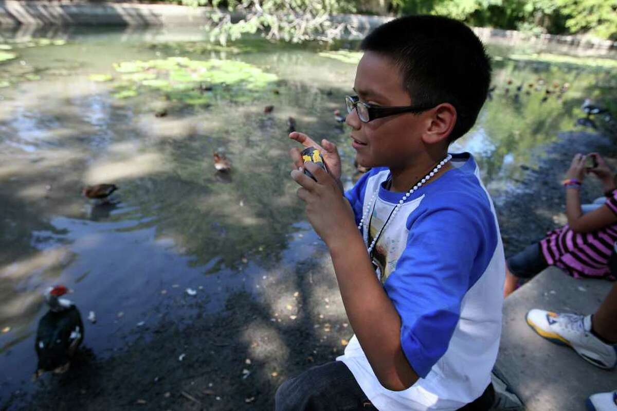 Ten-year-old Michael photographs waterfowl at Brackenridge Park on an outing Sunday as part of the “Pictures of Hope” program.