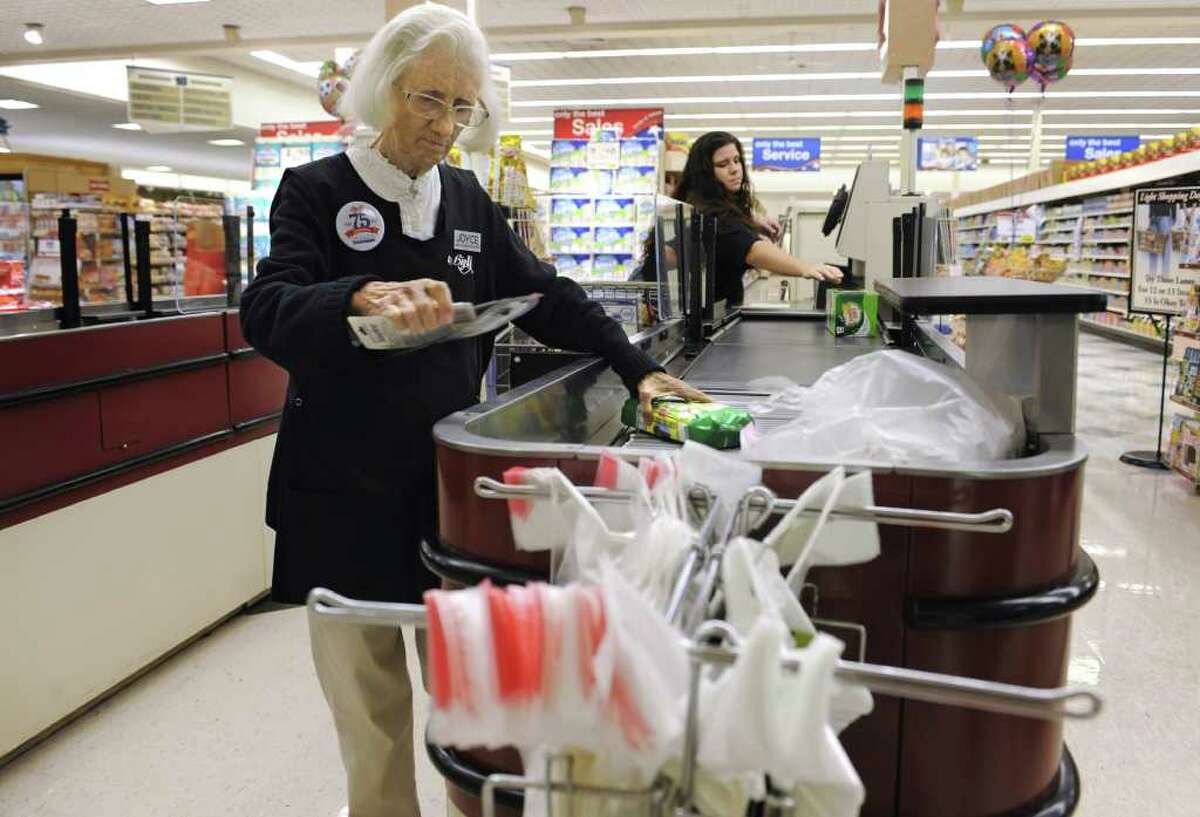 In this Sept. 23, 2011 photo, cashier Joyce Mackie bags groceries as a customer uses a self-serve checkout station at a Big Y supermarket in Manchester, Conn.