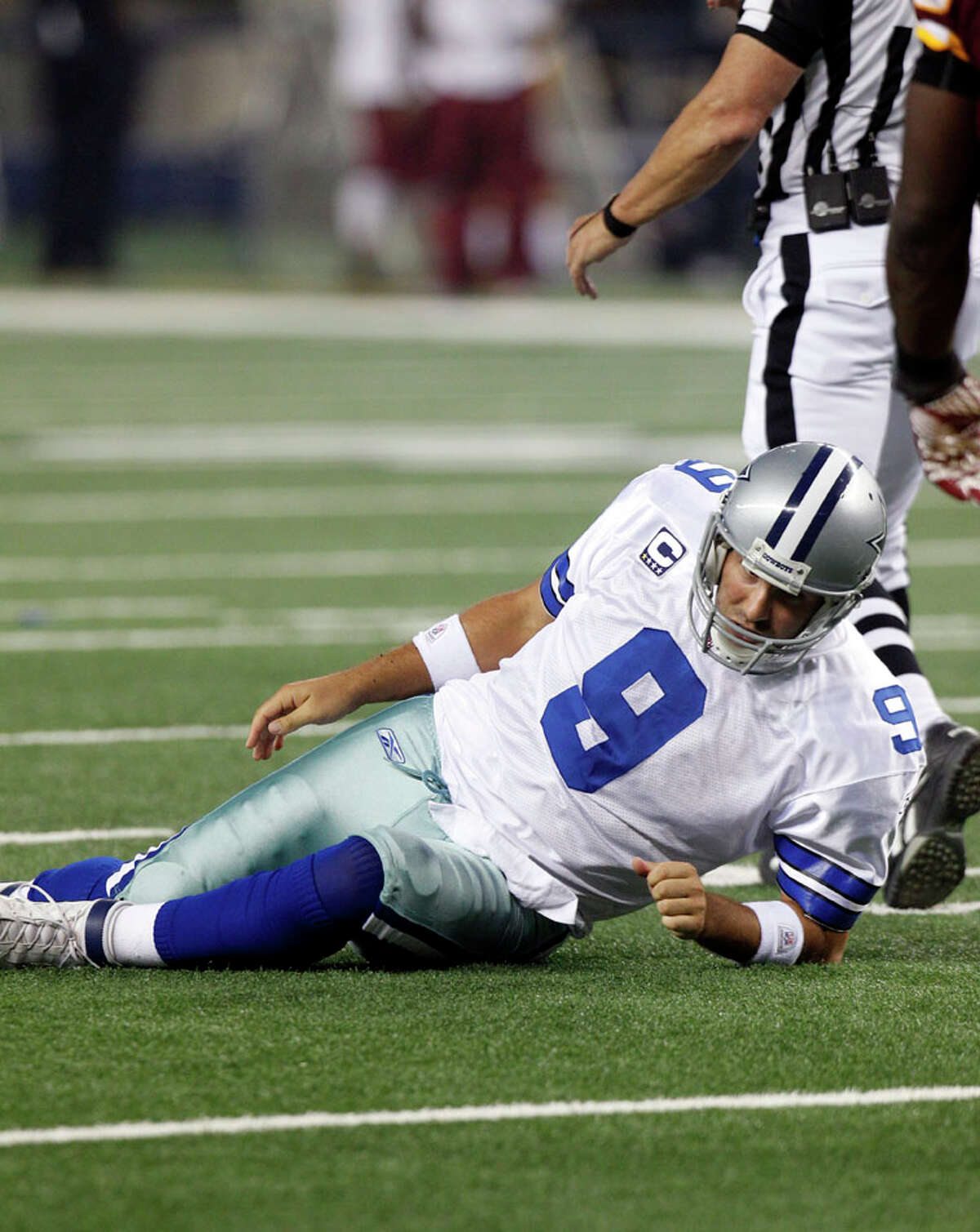 Dallas Cowboys quarterback Tony Romo lays on the turf after being knocked down by the Washington Redskins during the first half of an NFL football game Monday, Sept. 26, 2011, in Arlington.