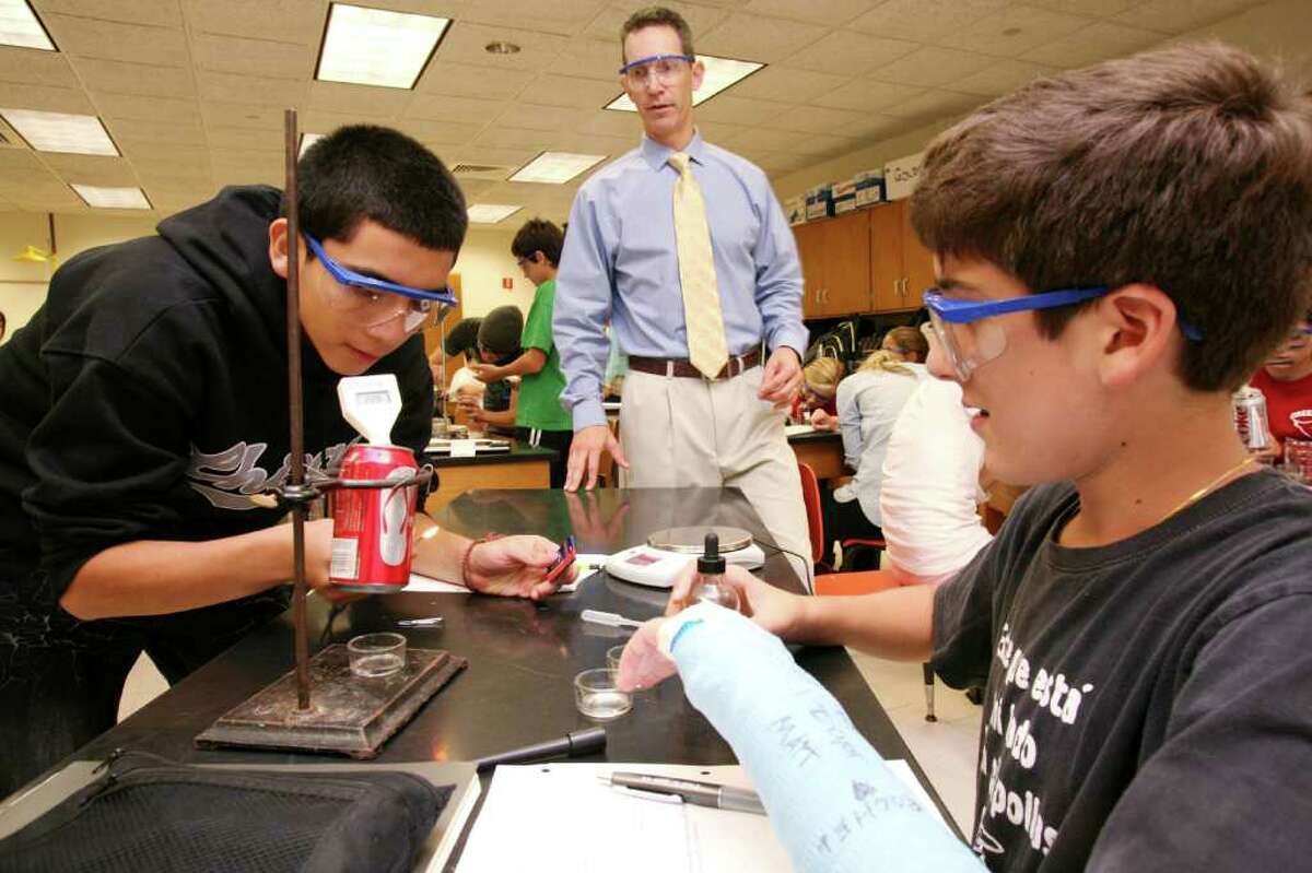 Greenwich High School science teacher Jason Goldstein, center, instructs freshman Moises Cebanos, left, and Steven Gil during an experiment Friday afternoon, Sept. 30, 2011, in the school's new integrated science course that emphasizes real world scenarios and problem solving.