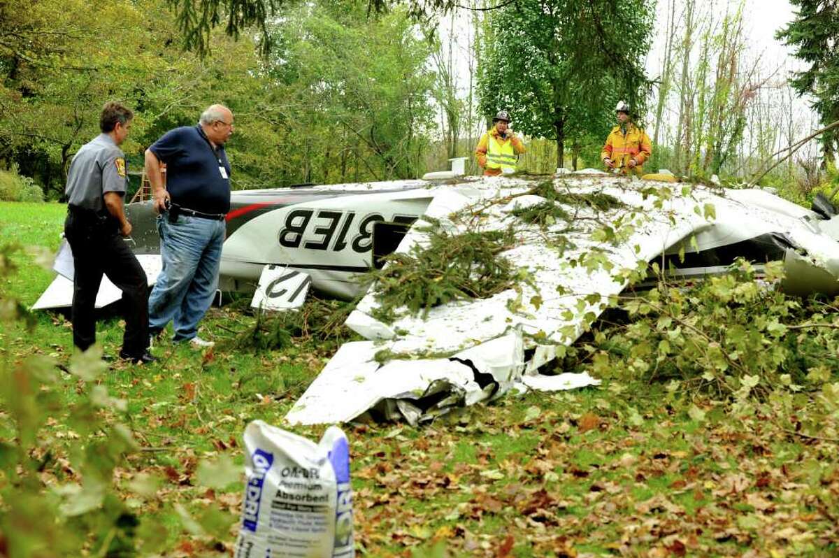 Fire and police officials including Paul Estefan, administrator of Danbury Municipal Airport examine a plane that crashed in front of a home on Briar Ridge Road in Ridgefield Saturday, Oct. 1, 2011.