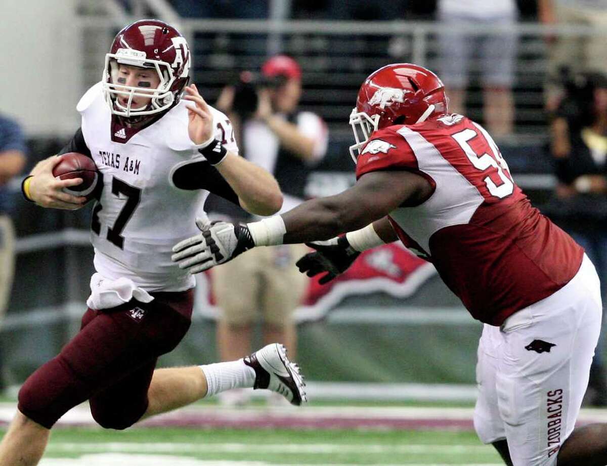 Texas A&M quarterback Ryan Tannehill tries to escape Arkansas’ Byran Jones on Saturday in Arlington. Arkansas won 42-38. Tannehill and the Aggies have blown three-possession halftime leads in their last two games.