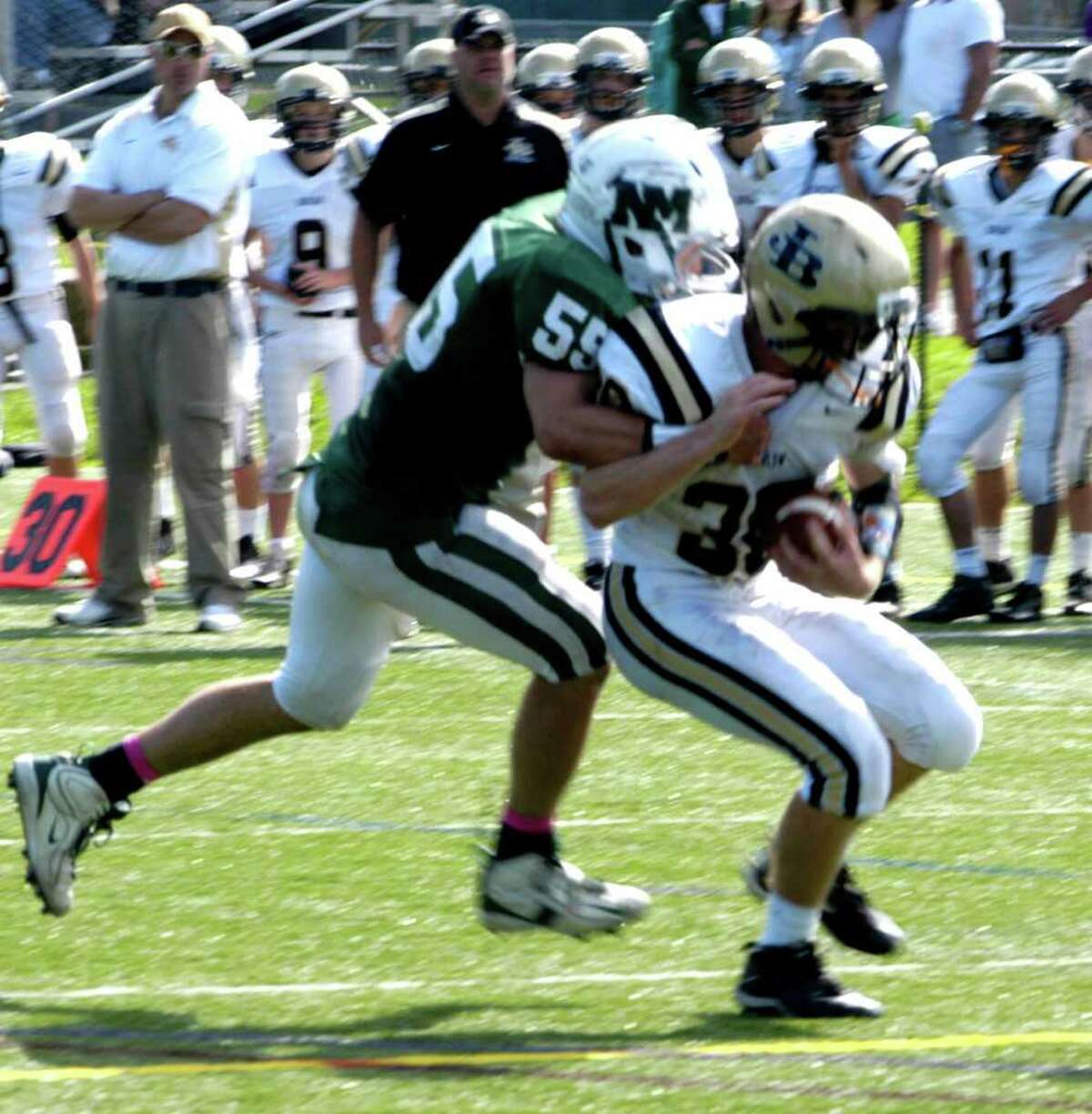 SPECTRUM/The Joel Barlow bench gets a good look as Green Wave defender Sean Doenias drags down a Falcon ballcarrier during New Milford High School football's 28-9 victory over Barlow, Sunday, Oct. 2, 2011 in Brookfield.