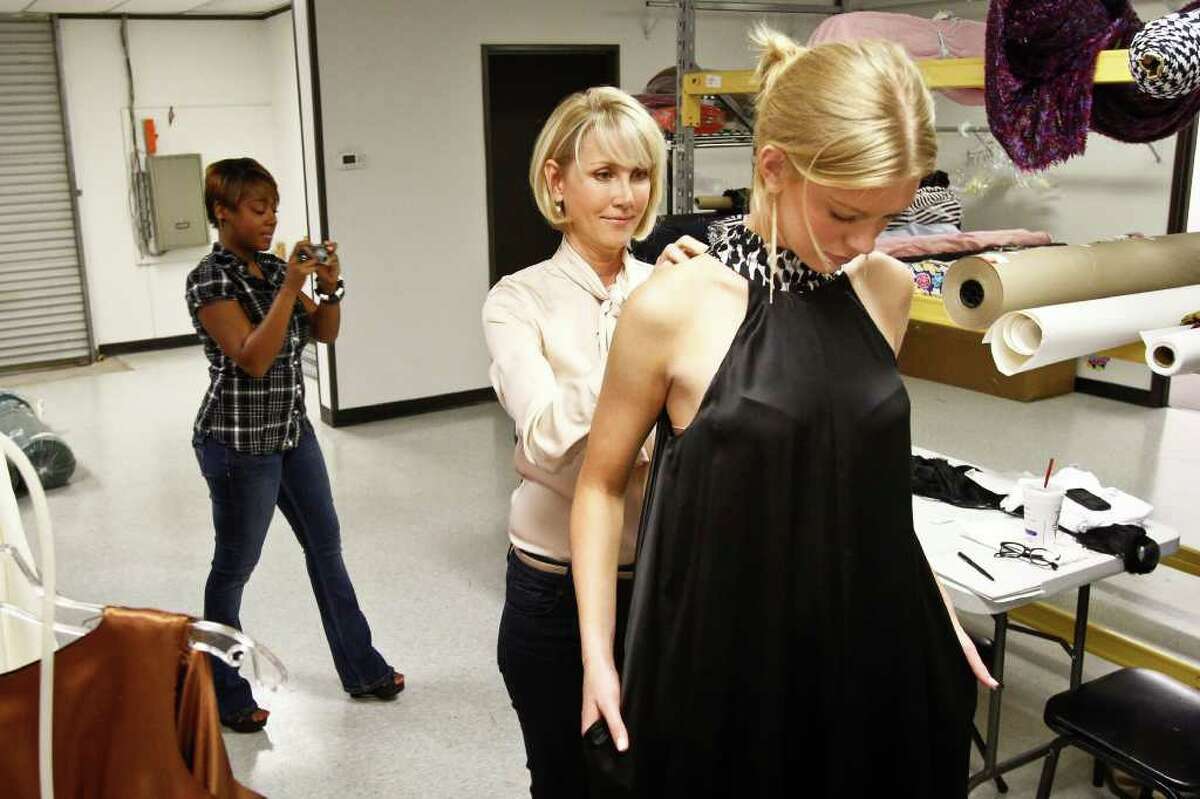 Houston fashion designer Jerri Moore (center) ties a bow around model Alyssa Pasek as design assistant Tanesha Seafous (left) takes a photo during a final fitting of Moore's collection for Fashion Houston, Tuesday, Sept. 27, 2011, in Houston. ( Michael Paulsen / Houston Chronicle )
