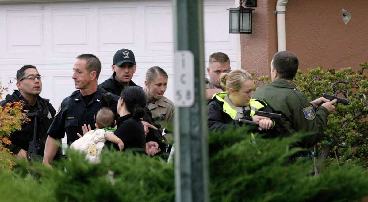 Sheriff's deputies escort a woman and baby out of a house before they enter the home in Sunnyvale, Calif., where a man matching the description of suspected gunman Shareef Allman was found and shot dead by law enforcement officers on Thursday, Oct. 6, 2011. Shareef was the focus of a huge manhunt after an alleged shooting at a Cupertino cement plant early Wednesday morning where three people were killed and seven wounded. (AP Photo/San Jose Mercury News, Gary Reyes)