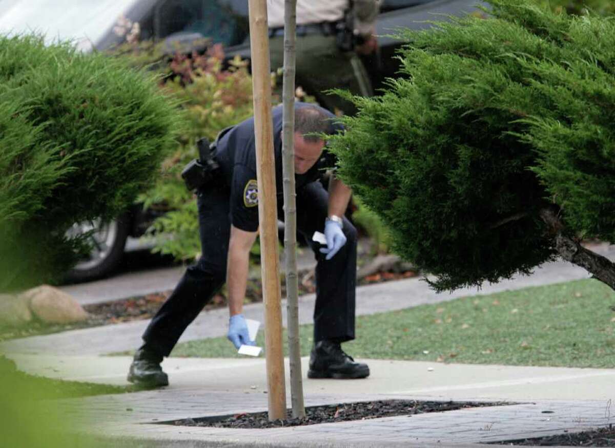 A law enforcement officer picks up evidence on Lorne Way in Sunnyvale, Calif., where a man matching the description of suspected gunman Shareef Allman was found and shot dead by law enforcement officers on Thursday, Oct. 6, 2011. Shareef was the focus of a huge manhunt after an alleged shooting at a Cupertino cement plant early Wednesday morning where three people were killed and seven wounded. (AP Photo/San Jose Mercury News, Gary Reyes)