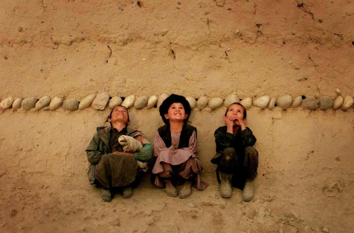 Afghan boys watch as U.S. Air Force planes fly overhead, dropping bombs on nearby Taliban tank positions, kicking off an assault against the Taliban.