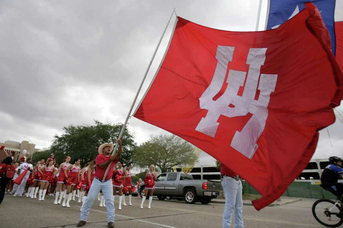 Gabe Salazar, a Frontiersman and UH student tries to hold up the UH flag as wind gusts past him before a NCAA football game at Robertson Stadium on Saturday, Oct. 8, 2011, in Houston.