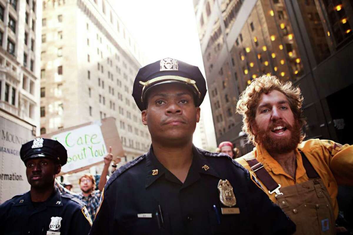 ANDREW BURTON : ASSOCIATED PRESS PROTEST PATROL: Two New York City police officers walk alongside a protester affiliated with the "Occupy Wall Street" protests outside Zuccotti Park in New York on Monday.