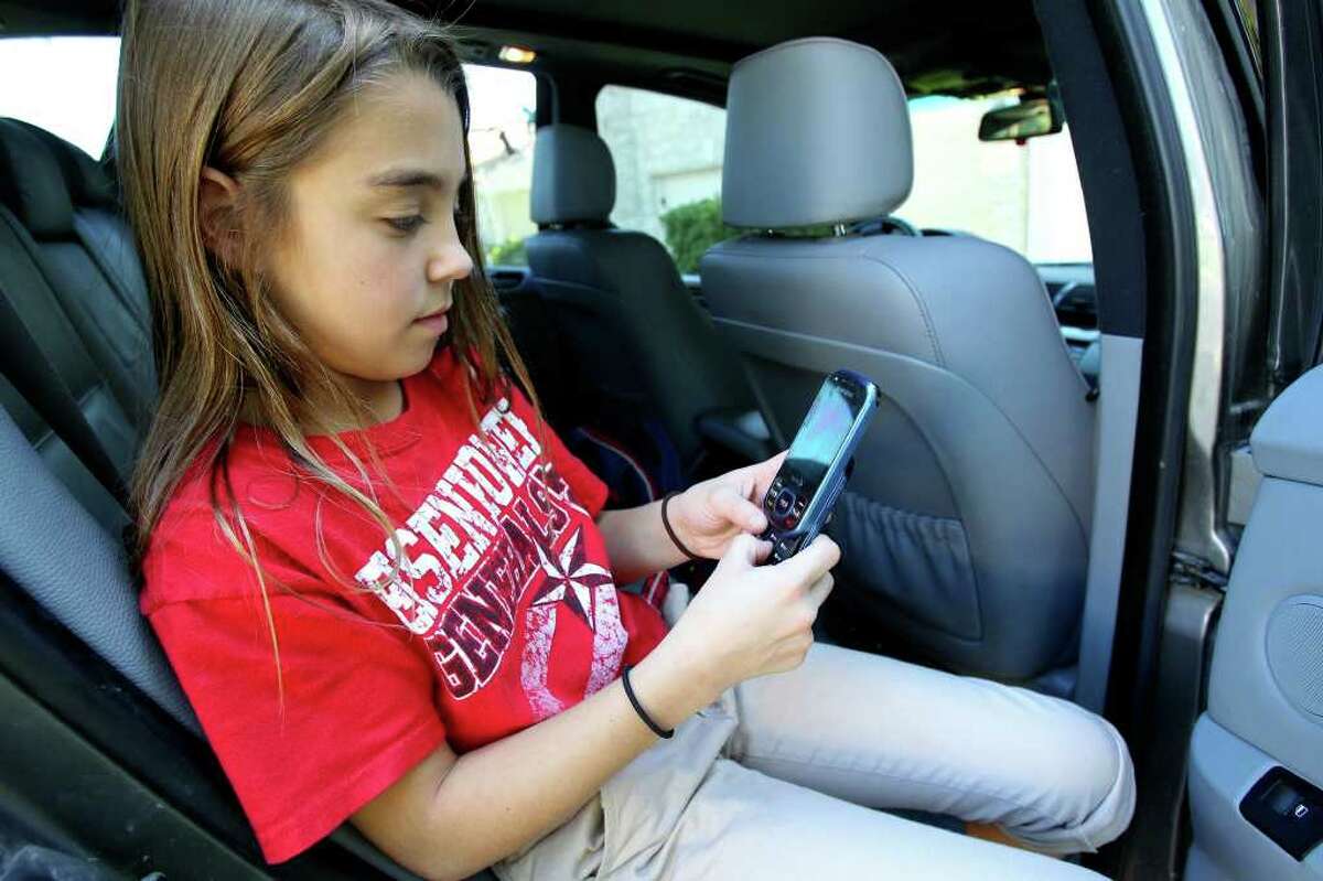 Eleven-year-old Devyn Darmstetter uses her phone while waiting in her dad’s car.