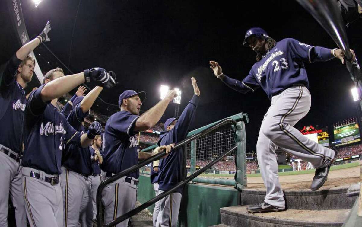 Milwaukee Brewers' Rickie Weeks is congratulated after scoring on a ball hit by George Kottaras during the sixth inning of Game 4 of baseball's National League championship series against the St. Louis Cardinals Thursday, Oct. 13, 2011, in St. Louis. (AP Photo/Matt Slocum)