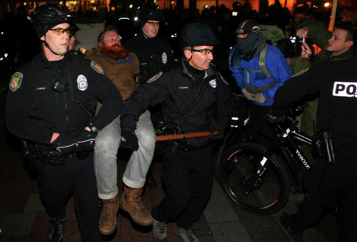 Seattle Police carry away an Occupy Seattle protester at Seattle's Westlake Park on Thursday, October 13, 2011. Ten protesters were arrested for refusing to move from a makeshift structure in the park. Earlier city officials said that people needed to clear from the park at 10 p.m. when it closes. Eventually police withdrew, causing the crowd gathered to erupt in cheers.