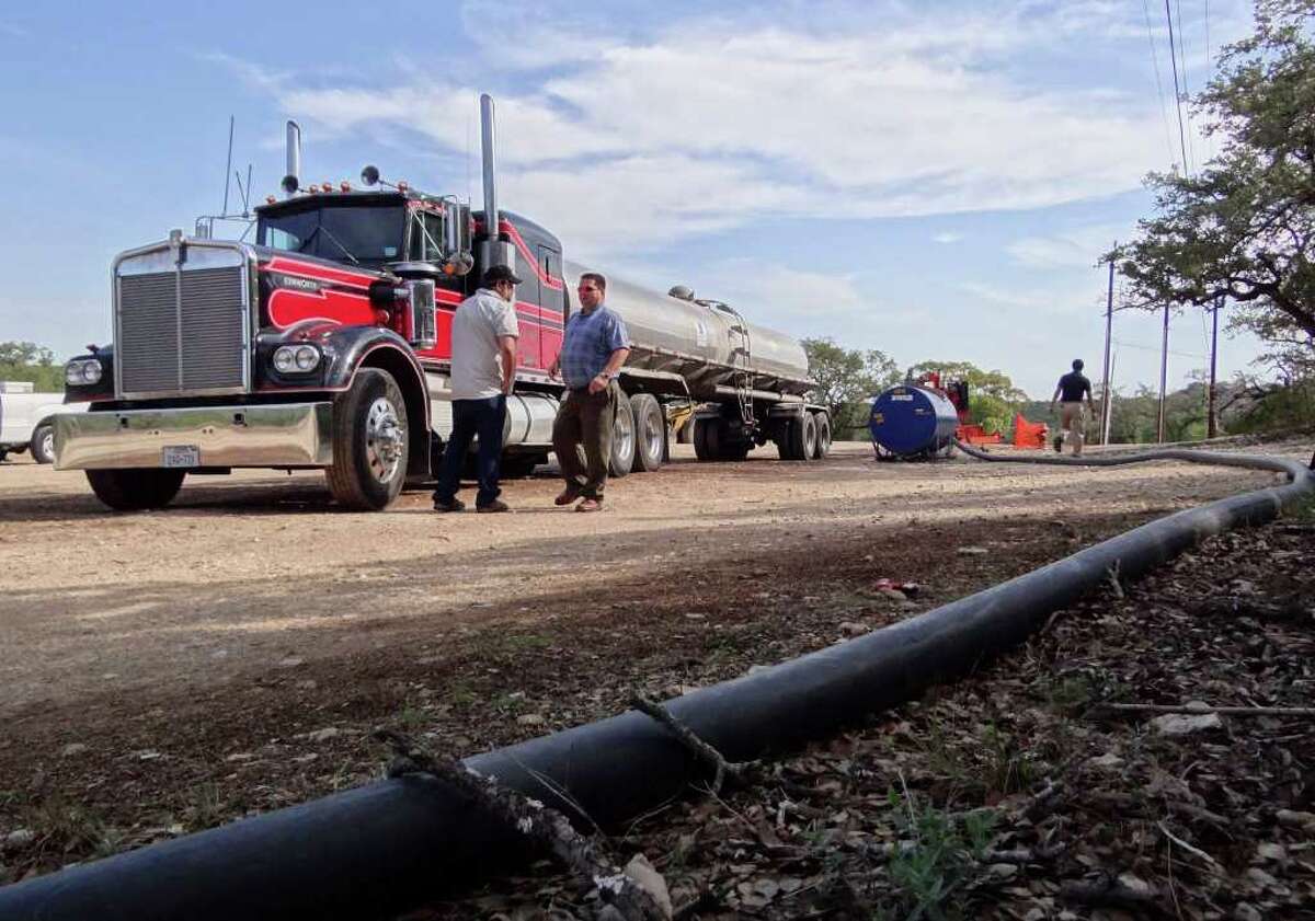 A truck driven by Buddy Dixon, left, is hooked up to a pump moving water through a line into the Anaqua Springs Ranch community on behalf of BexarMet on Friday, Sept. 30, 2011.